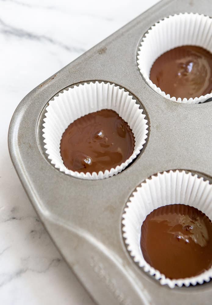 Add melted chocolate to muffin liners to make almond butter chocolates