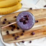 Blueberry mango banana smoothie topped with frozen blueberries