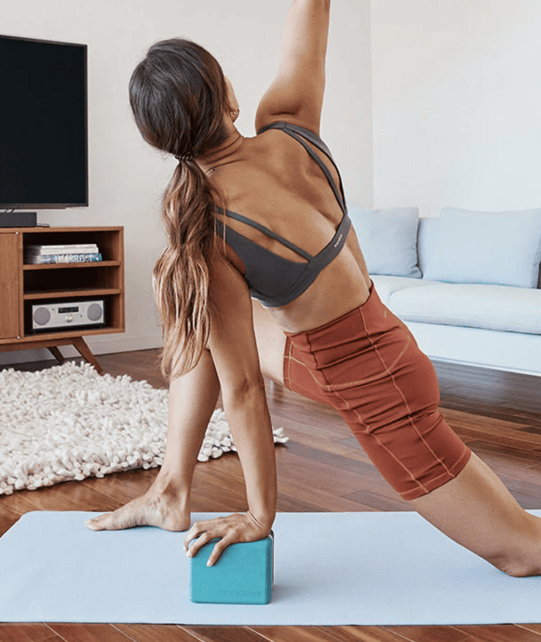 A girl doing yoga on a mat with a yoga brick