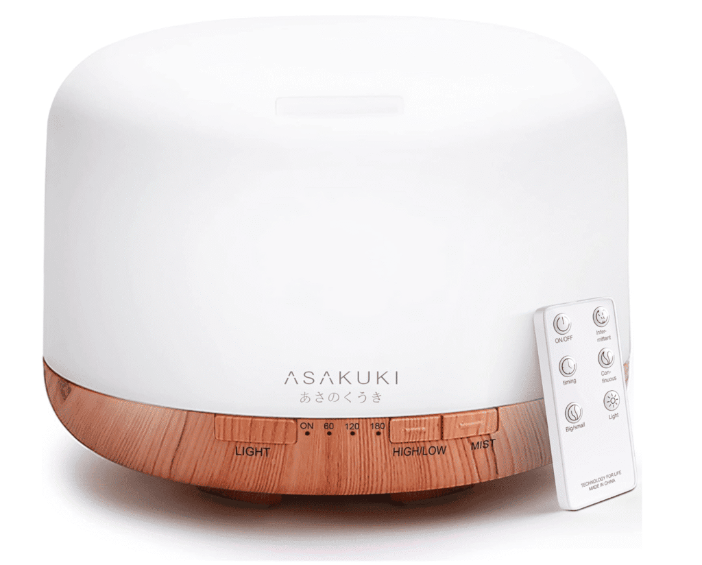 A white essential oil diffuser with a remote on the side