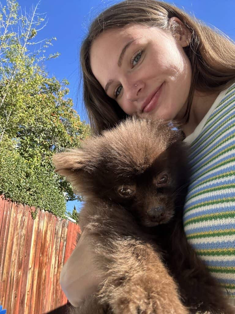 Natalie, from Nourished with Natalie, holding a small brown dog.
