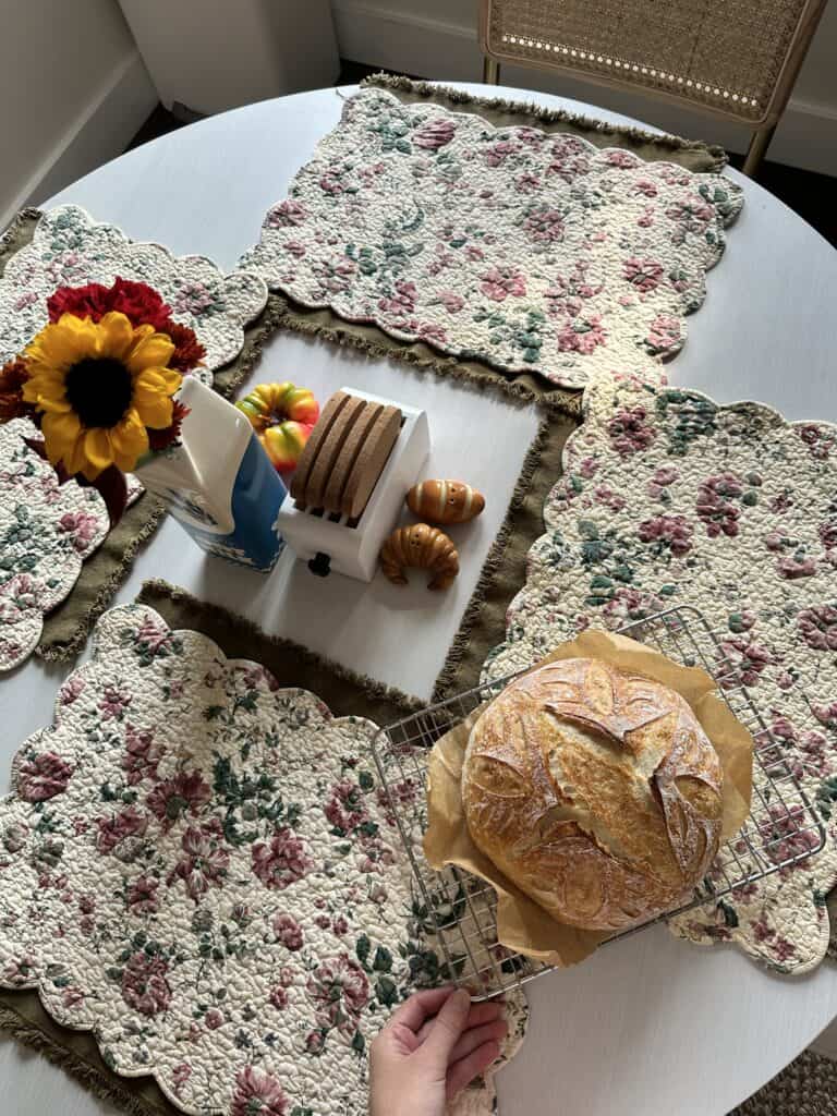 A fresh loaf of sourdough on a table with placemats.