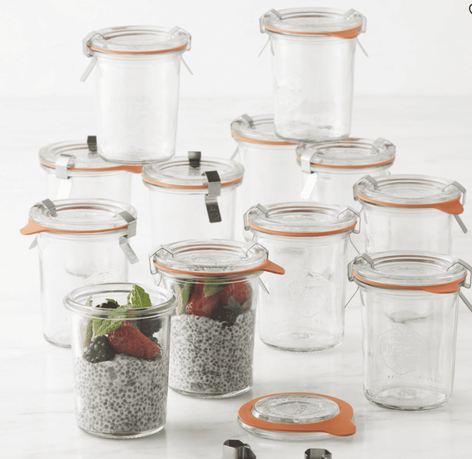 12 weck jars sitting on a granite countertop with two filled with chia pudding.