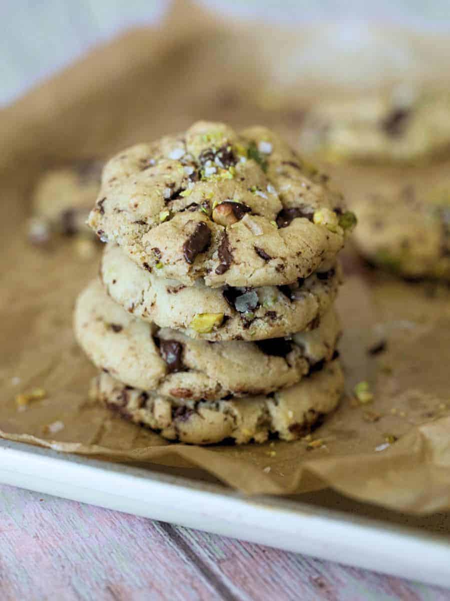 A stack of four pistachio chocolate chip cookies on a piece of parchment