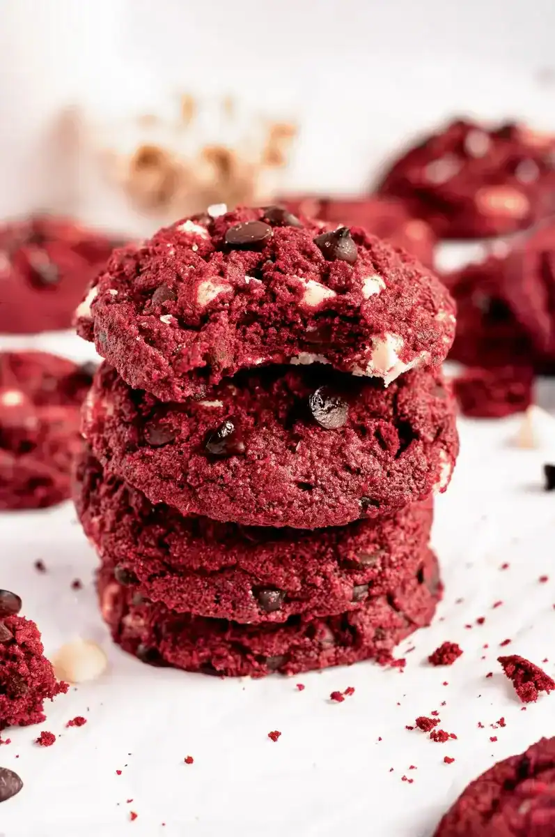 A stack of four red velvet cookies with a bite taken out of the top one.