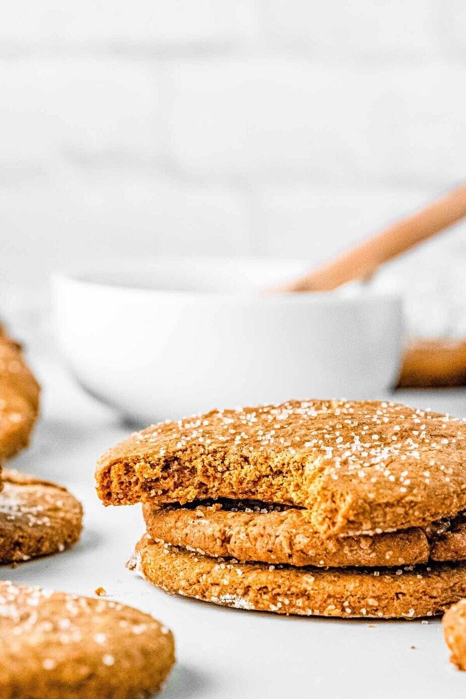 A stack of vegan gingerbread cookies with one on top with a bite out of it.