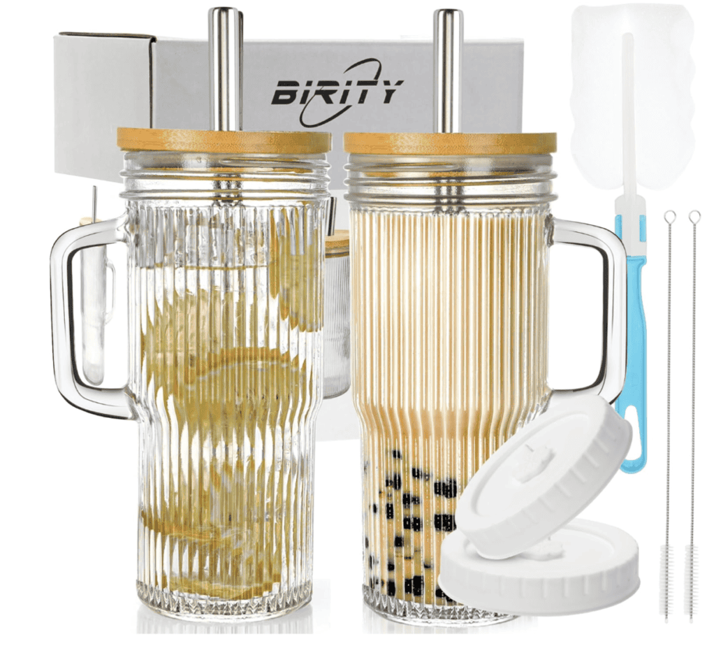 Two ribbed glass cups with bamboo lids and stainless steel straws.