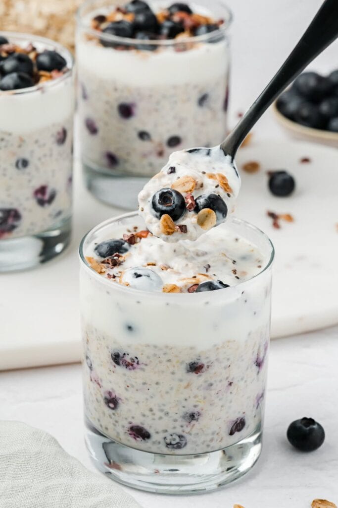 A glass of overnight oats with blueberries, lemons, and granola.