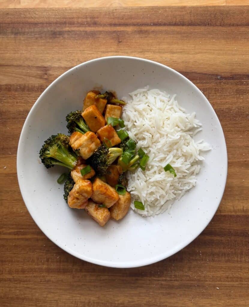 A bowl of rice and broccoli with tofu and green onions