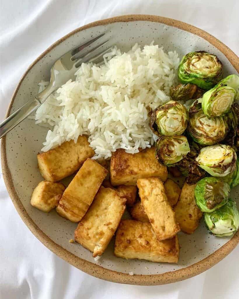 A bowl of rice, tofu, and brussels sprouts