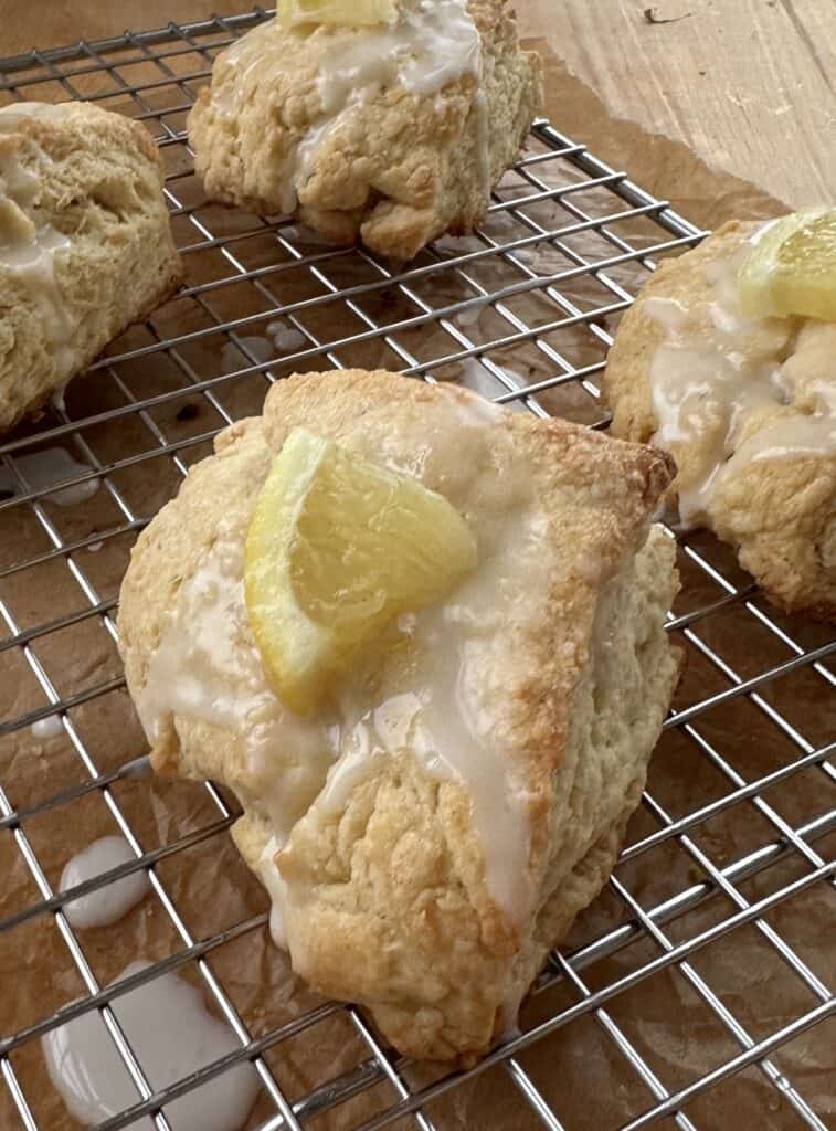 A close up of lemon scones topped with icing and a piece of lemon