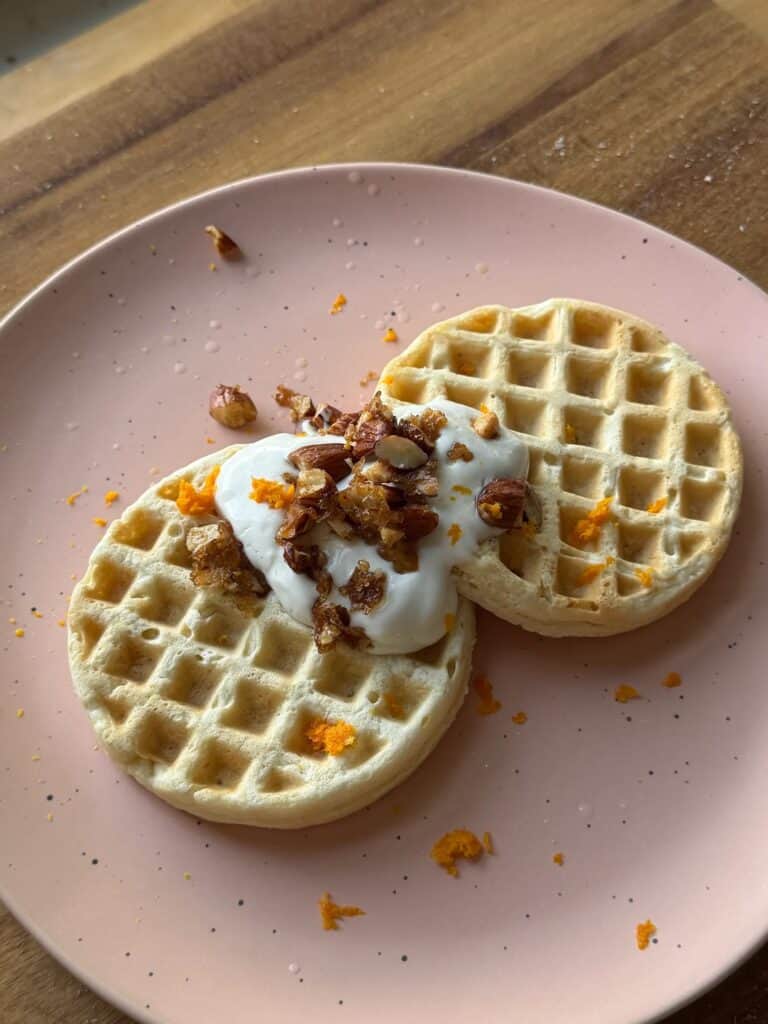 Orange waffles topped with candied almonds and orange zest