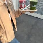 Girl holding smoothies in a lightweight jacket and jeans