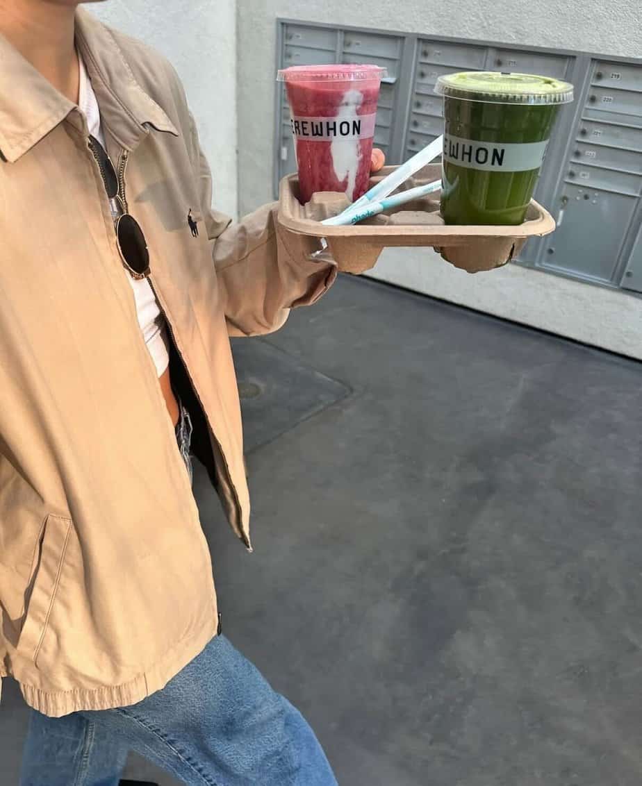 Girl holding smoothies in a lightweight jacket and jeans
