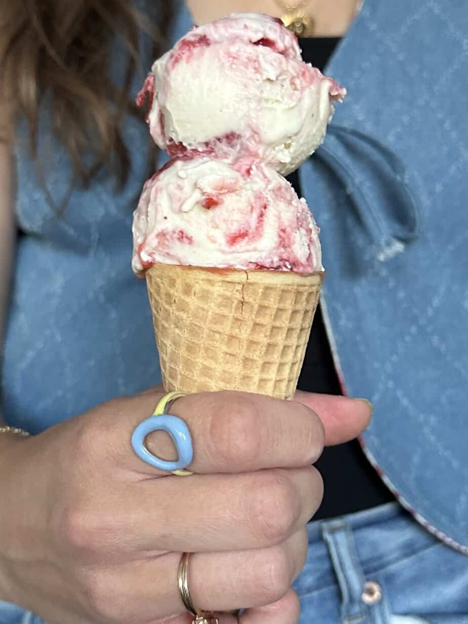 A scoop of corn and strawberry ice cream in a cone