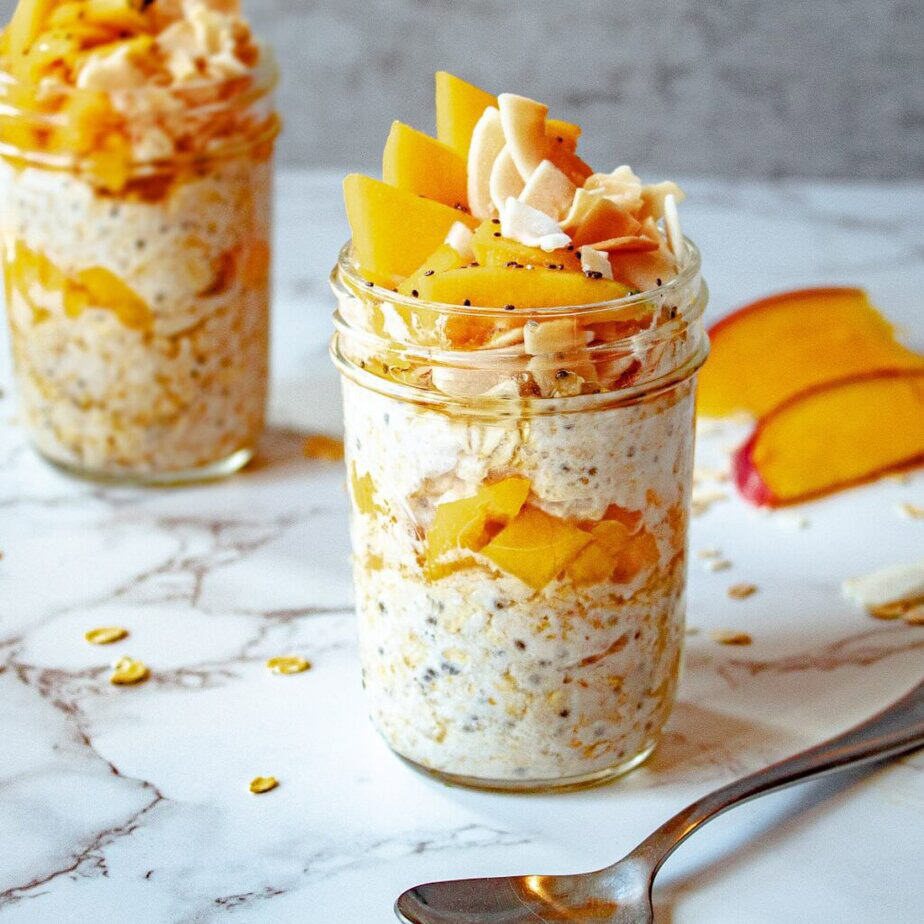 A jar of overnight oats topped with mango and coconut.