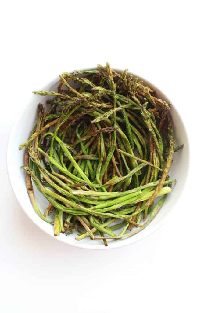 Top down shot of air fried asparagus in a white bowl