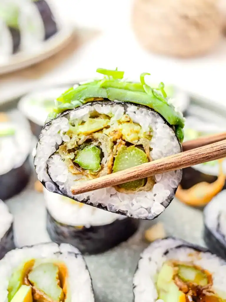 Close up of sushi roll filled with tempura asparagus and avocado.