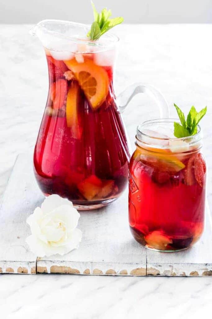 A jug of non-alcoholic sangria with a glass next to it