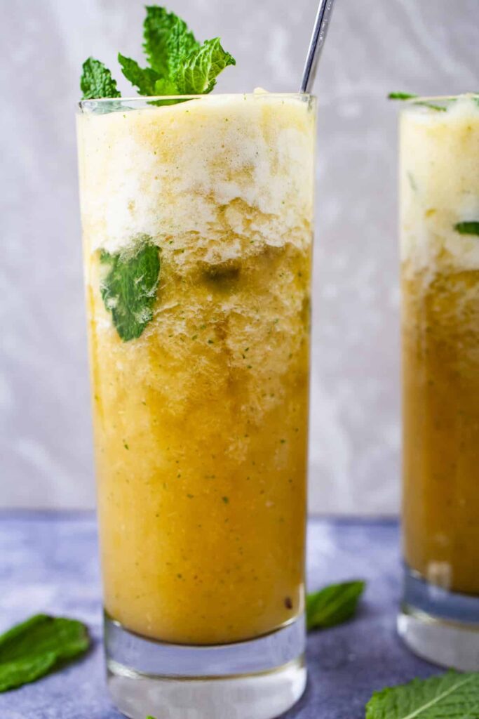A sparkling pineapple mojito mocktail in a clear glass garnished with mint