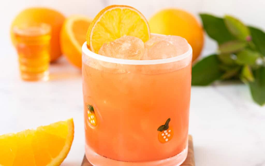 A virgin margarita in a glass cup adorned with oranges and garnished with oranges