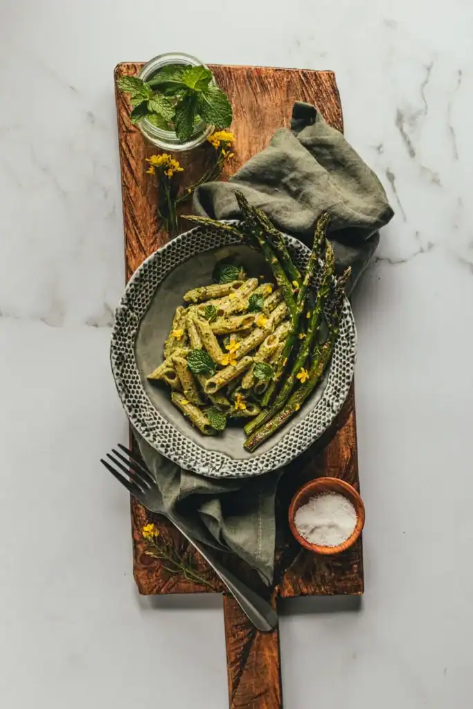 Top down shot of a bowl of pasta topped with basil, asparagus, and mint.