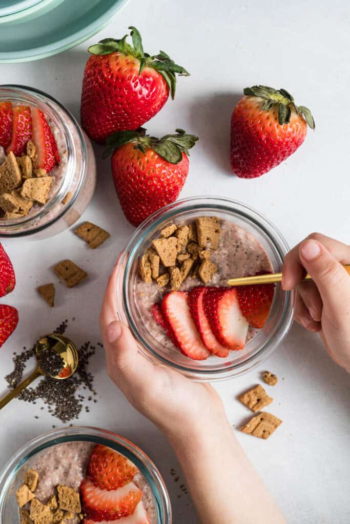Top down shot of strawberry chia pudding in three glass bowls topped with strawberries and graham crackers