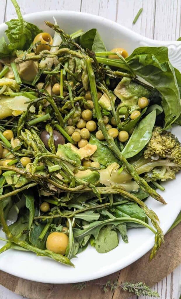 A white dish packed with wild asparagus, sweet peas, creamy avocado, and loads of fresh herbs.
