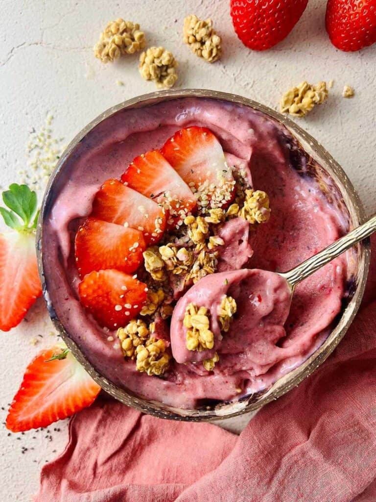 Top down shot of strawberry banana smoothie bowl topped with strawberries and granola