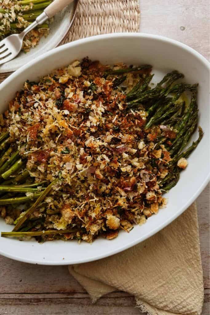 Roasted asparagus topped with a crisp topping in a casserole dish.